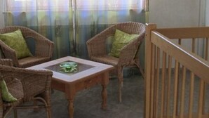 A balcony with wicker furniture, a small table, and a wooden railing. - Apartment im Dresdner Amselgrund (Dresden)