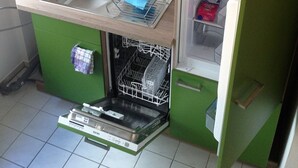Una cocina compacta con un lavamanos, un escurreplatos, un lavavajillas y un refrigerador pequeño.