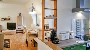 Un espacio habitable compacto con comedor, kitchenette y televisor.