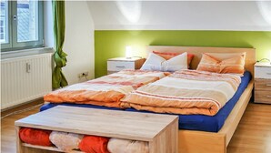 Un dormitorio con cama de madera, una mesita de noche y un ventanal con cortinas.