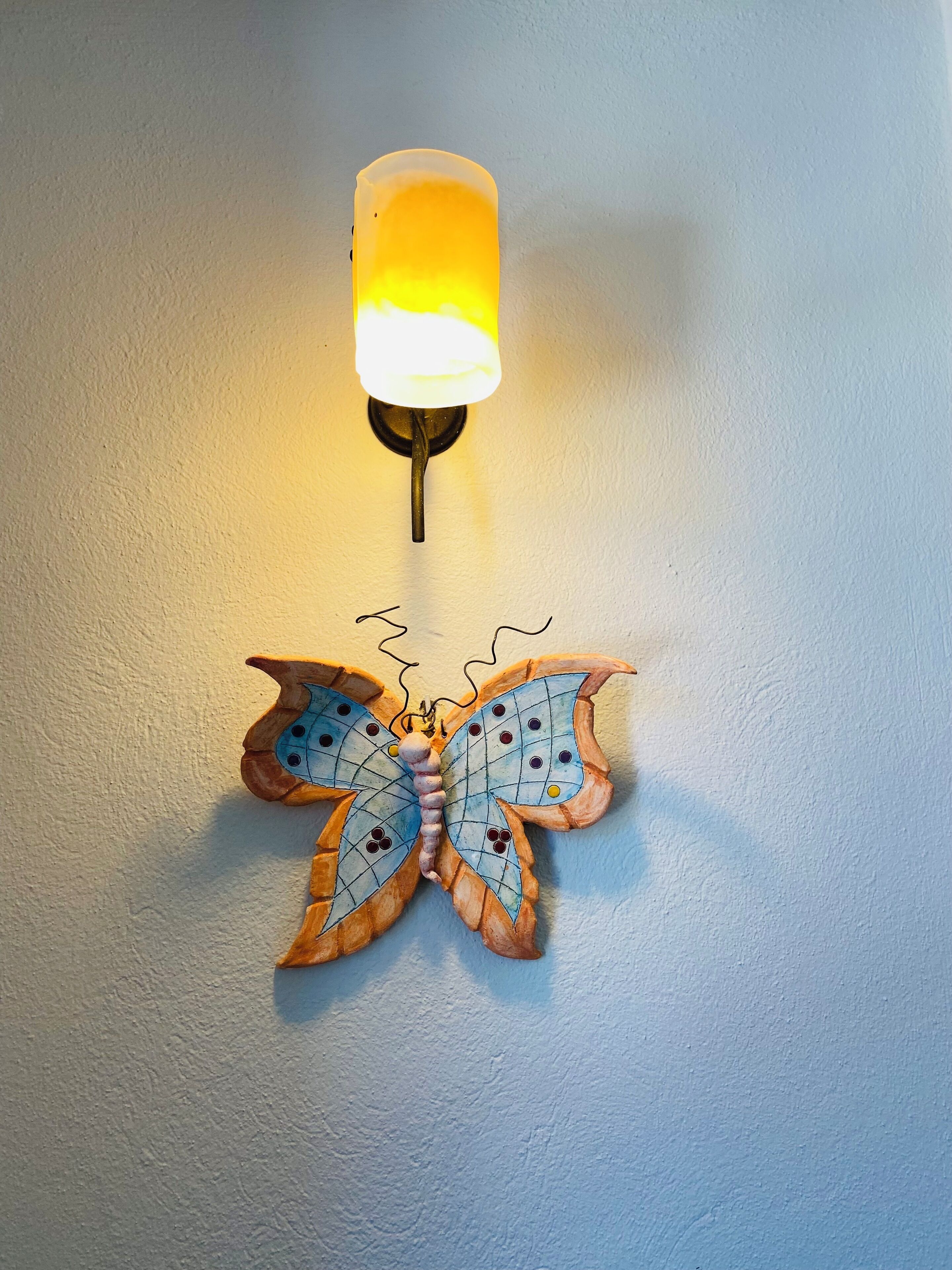 A wall-mounted butterfly light fixture with a warm glow.
