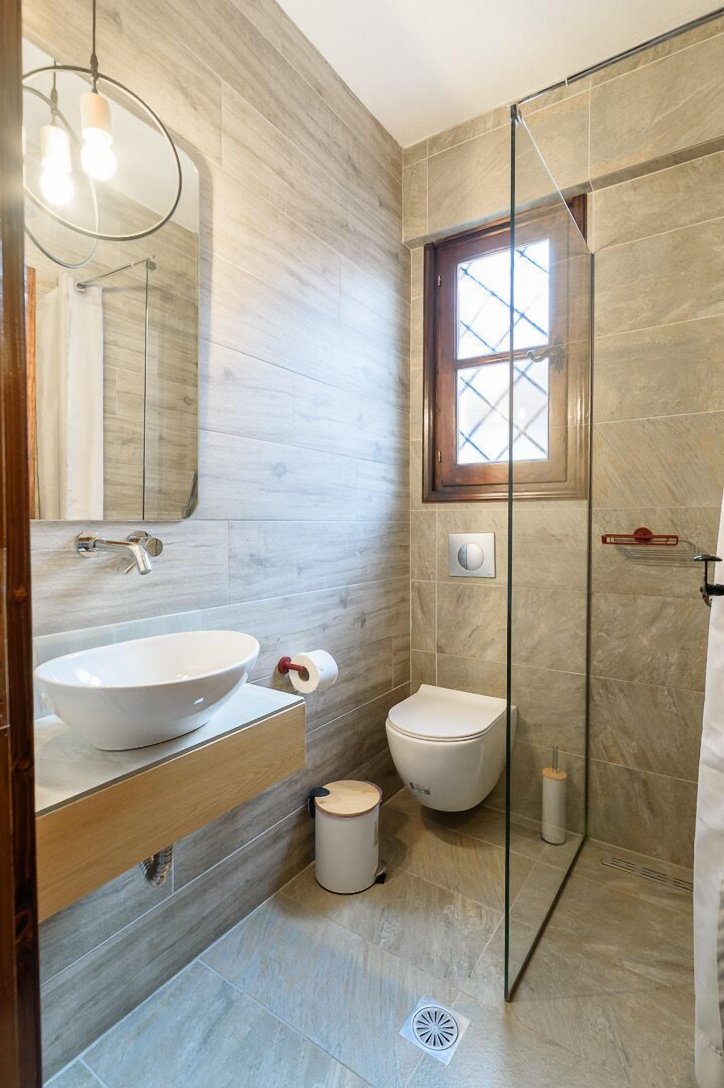 Une salle de bain moderne avec un grand lavabo sur pied, des toilettes et une douche à parois de verre.