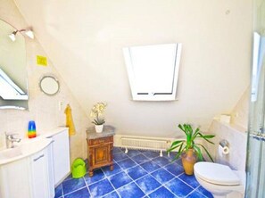 A bathroom with a white sink, a wooden vanity, a toilet, and a shower area.