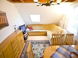 A cozy living room with a sofa, a wooden cabinet, a small table, and a patterned rug.