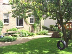 A brick building with a grassy lawn, a bench, and a tire swing.