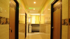 Un pasillo de hotel con puertas de madera, un mostrador de recepción y piso de baldosas.