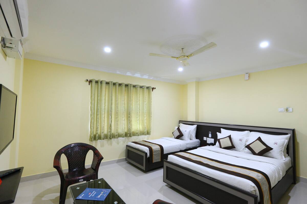 A hotel room with two beds, a desk with a computer, a chair, and a window with curtains.