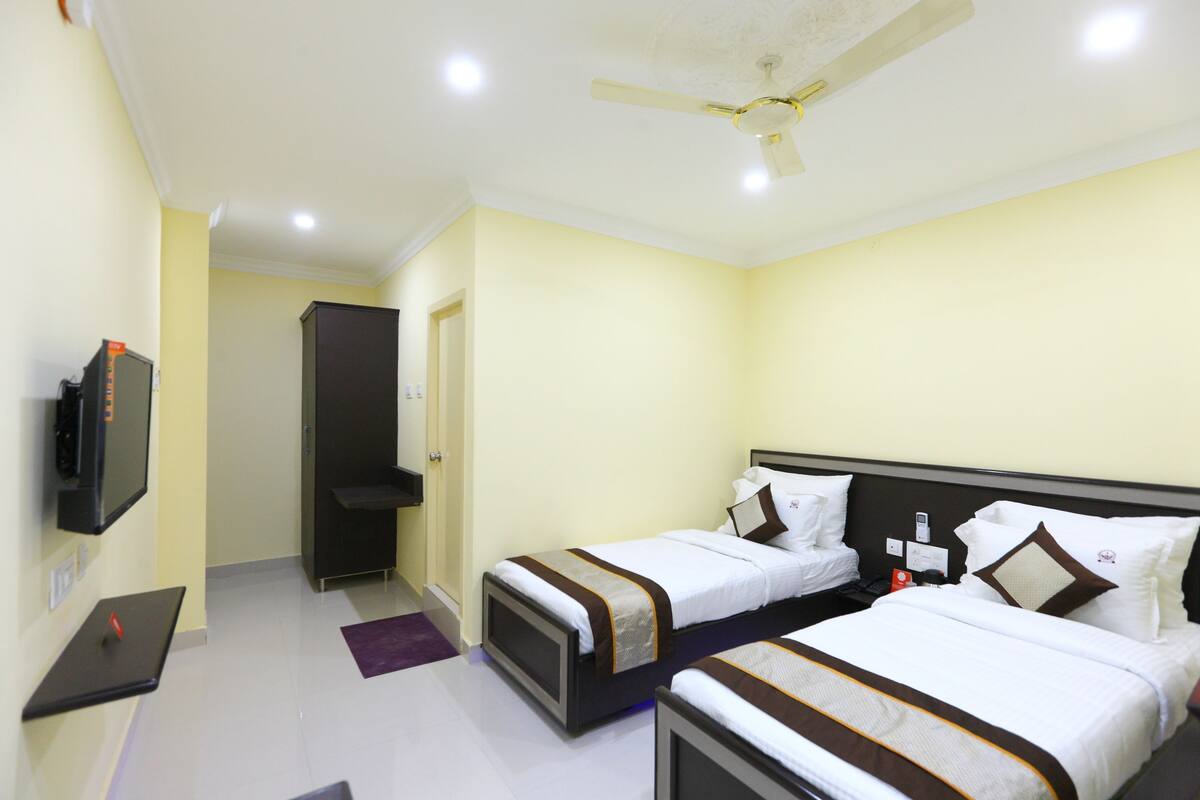 A hotel room with two beds, a TV, and a ceiling fan.