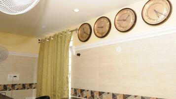 Un baño con tres relojes de pared, un ventilador y una cortina de ducha.