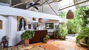 Un vaste espace intérieur doté d’un sol carrelé orné d’un motif géométrique, d’un comptoir d’accueil, de plantes en pot et d’un ventilateur de plafond.