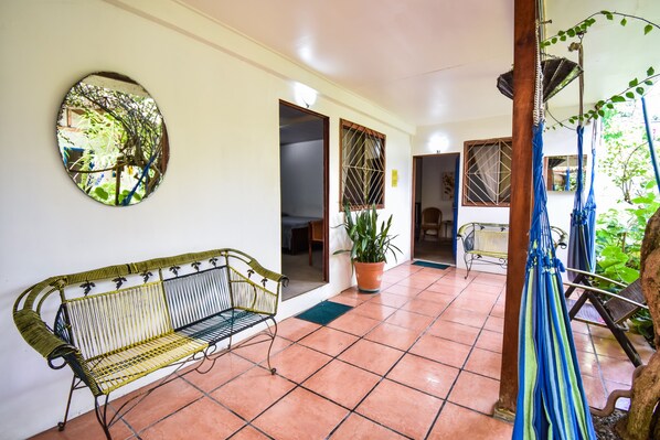 A spacious patio with a bench, a hammock, and a potted plant. - Jacaranda Hotel & Jungle Garden (Cahuita)