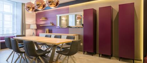 A modern dining area with a wooden table, black chairs, and a large mirror above.