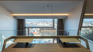 A modern room with a glass table and chairs, large windows offering a city view. - Castle Apartments Budapest (Budapest)