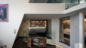 A modern living room with a glass staircase, a built-in bookshelf, and a flat-screen TV. - Castle Apartments Budapest (Budapest)