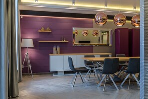 Un comedor moderno con una mesa de madera, sillas negras y una pared de acento morada.