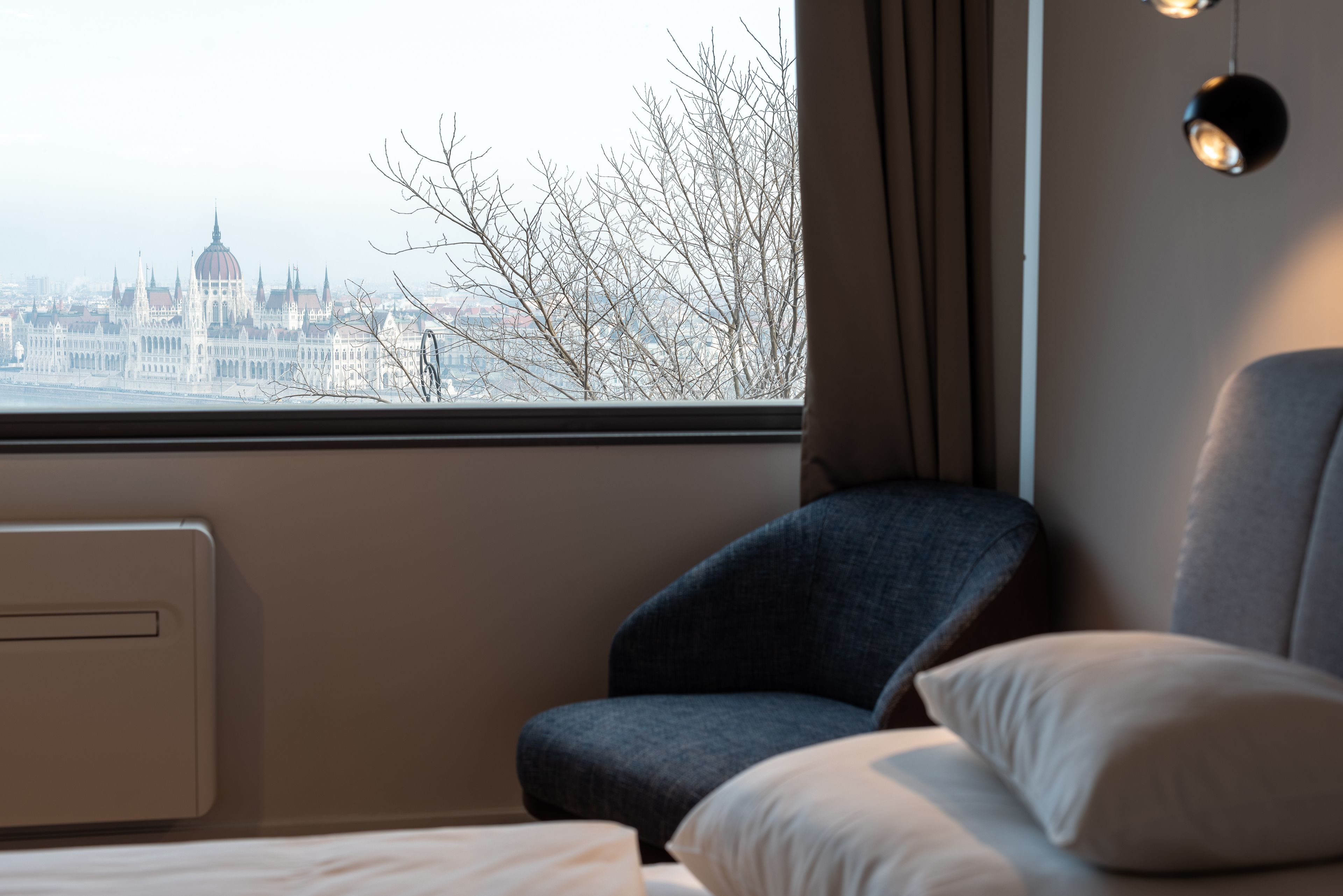 A hotel room with a view of a cityscape, including a prominent building with a dome.