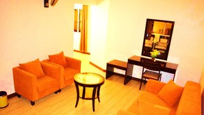 A living room with two orange sofas, a small round table, and a TV stand with a flat-screen TV.