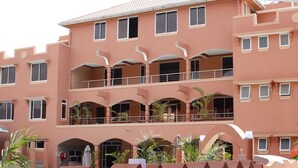 A multi-story hotel with balconies, outdoor plants, and a central entrance.