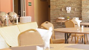 A clean, well-maintained outdoor dining area with wicker chairs and tables, a stone wall, and a visible washroom sign.