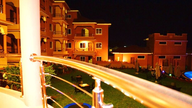 A nighttime view of a residential building with multiple balconies and a well-lit lawn area.