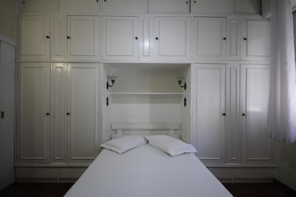 Un dormitorio con cama, armario blanco y estanterías empotradas.