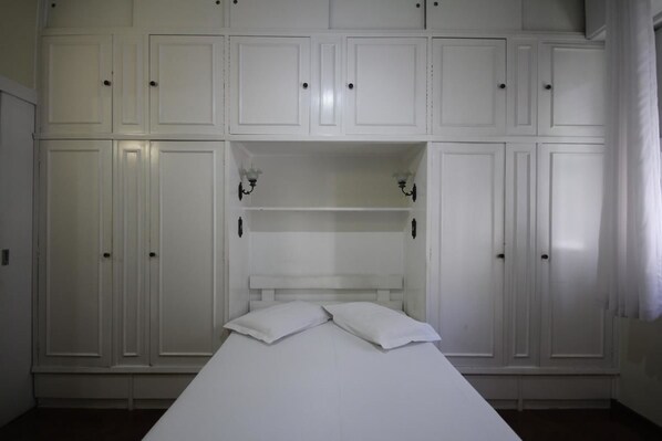 Une chambre à coucher avec un lit, une armoire blanche et des étagères intégrées.