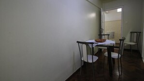 Een smalle gang met een eettafel, stoelen, een wit tafelkleed en een schaal op de tafel.