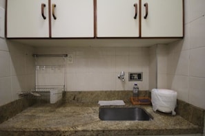 A kitchen with granite countertops, a sink, a toaster, and a dish rack.