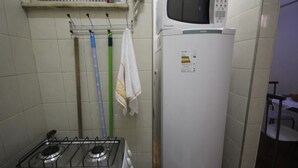 Een keuken met een gasfornuis, een magnetron en een koelkast.