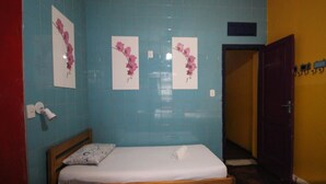A small, single-bed room with a wooden headboard, a white mattress, and a floral wall decoration. - GoHouse Torre 16 (Rio de Janeiro)