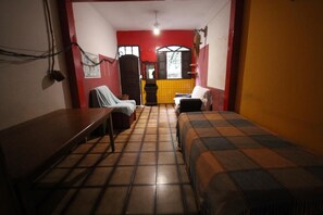 A small, narrow room with two beds, a bench, and a small table. - GoHouse Torre 16 (Rio de Janeiro)