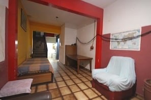 Quarto com uma cama, uma cadeira estofada, uma mesa e um mapa na parede.