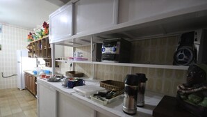 A kitchen with white cabinets, a microwave, a kettle, and various kitchen utensils. - GoHouse Torre 16 (Rio de Janeiro)
