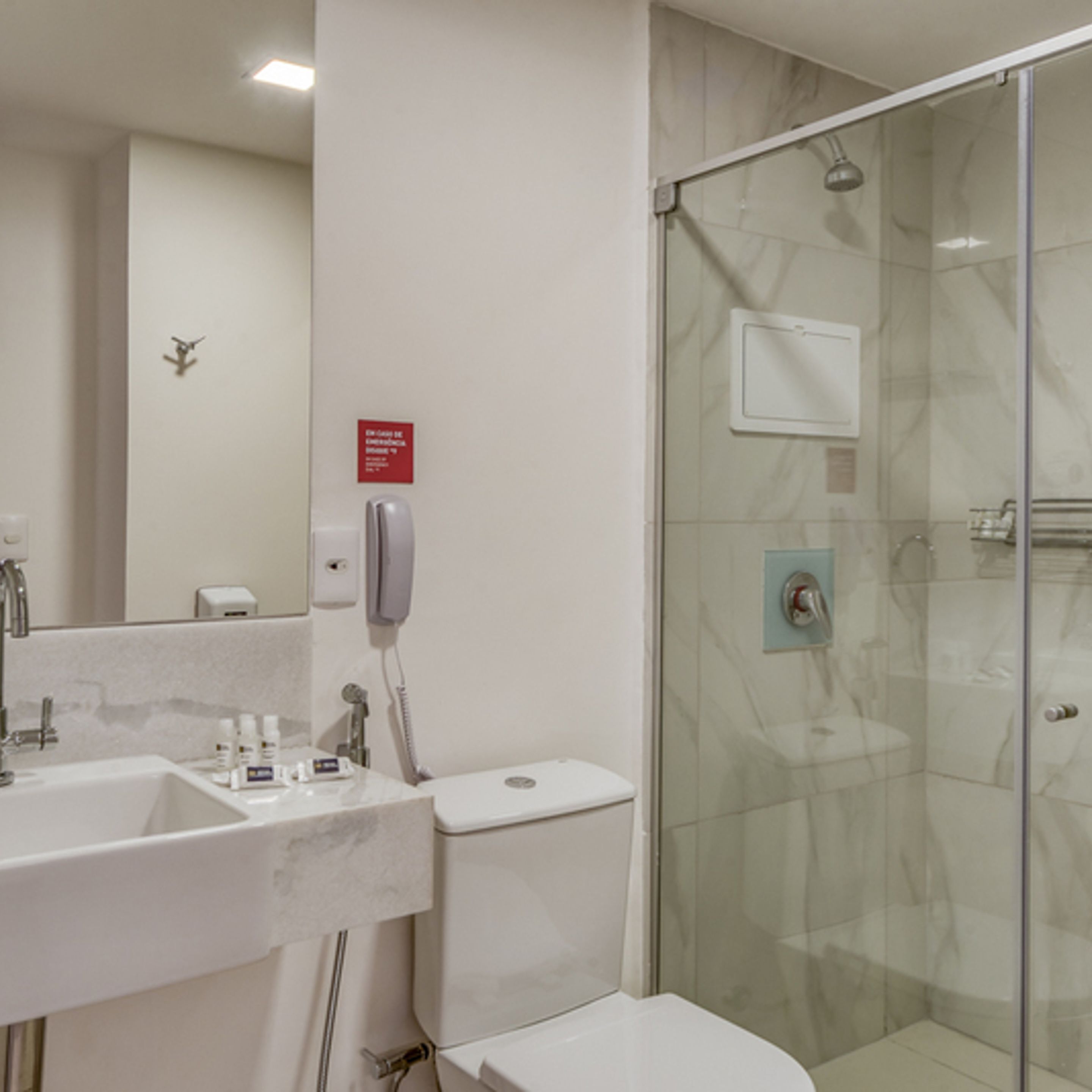 Un baño moderno con ducha de mampara de vidrio, un lavamanos blanco y un inodoro.