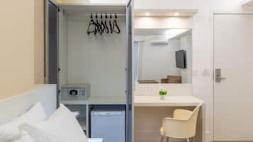Una habitación de hotel moderna con cama, escritorio, silla, mini refrigerador, televisor y puerta.