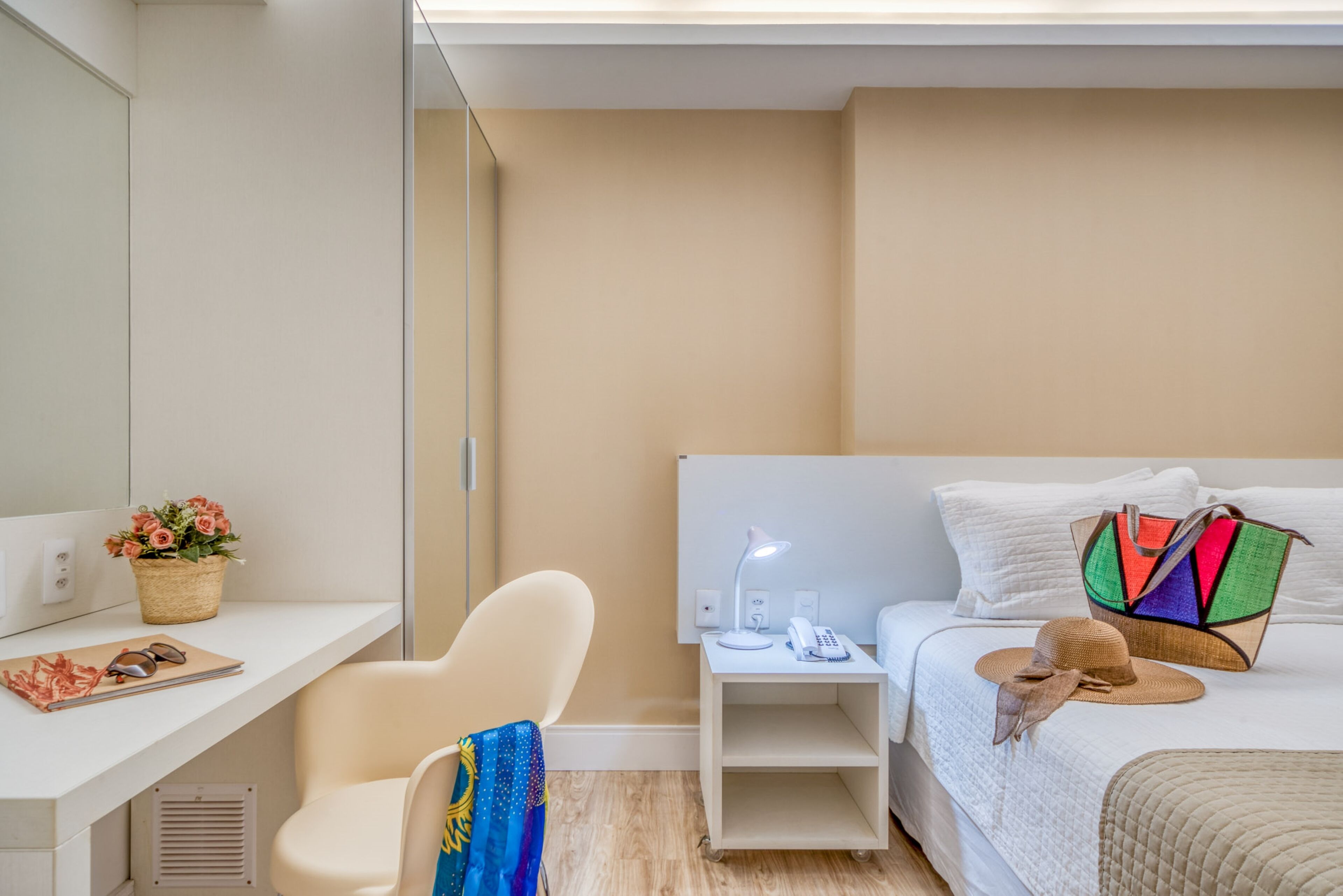 Habitación de hotel con cama, escritorio, silla, mesita de noche y velador.