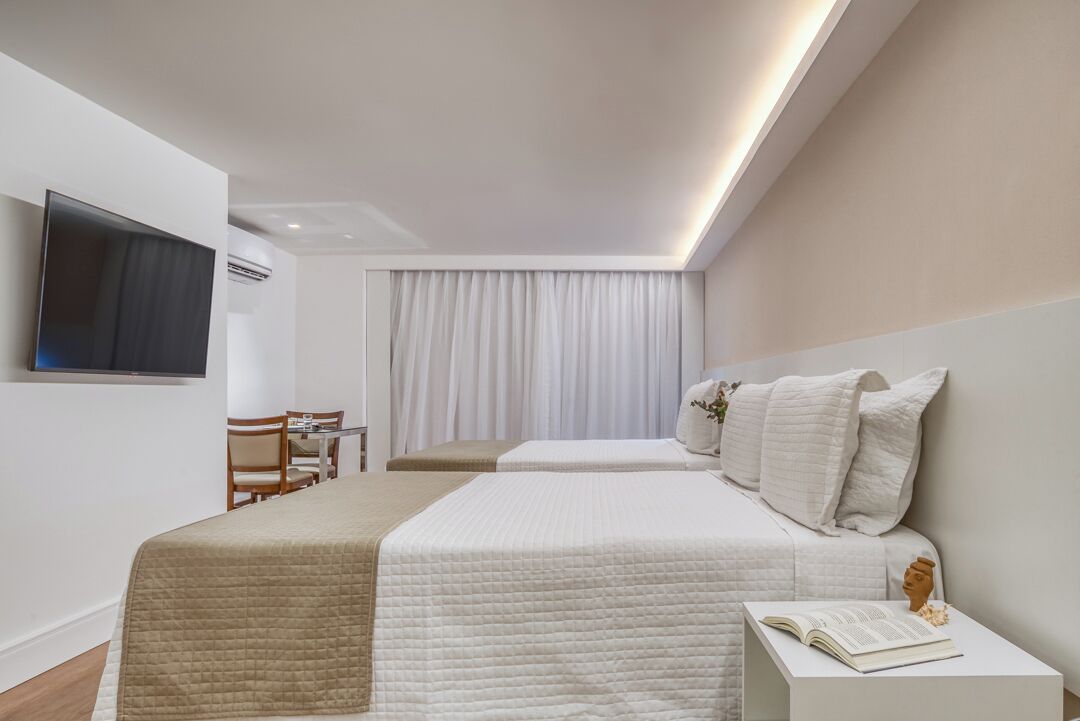 A modern hotel room with two beds, a flat-screen TV, a desk with a chair, and a large window with curtains.