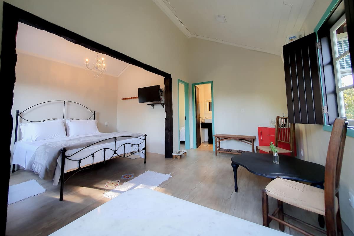 A bedroom with a bed, a TV, a table, and a chair.