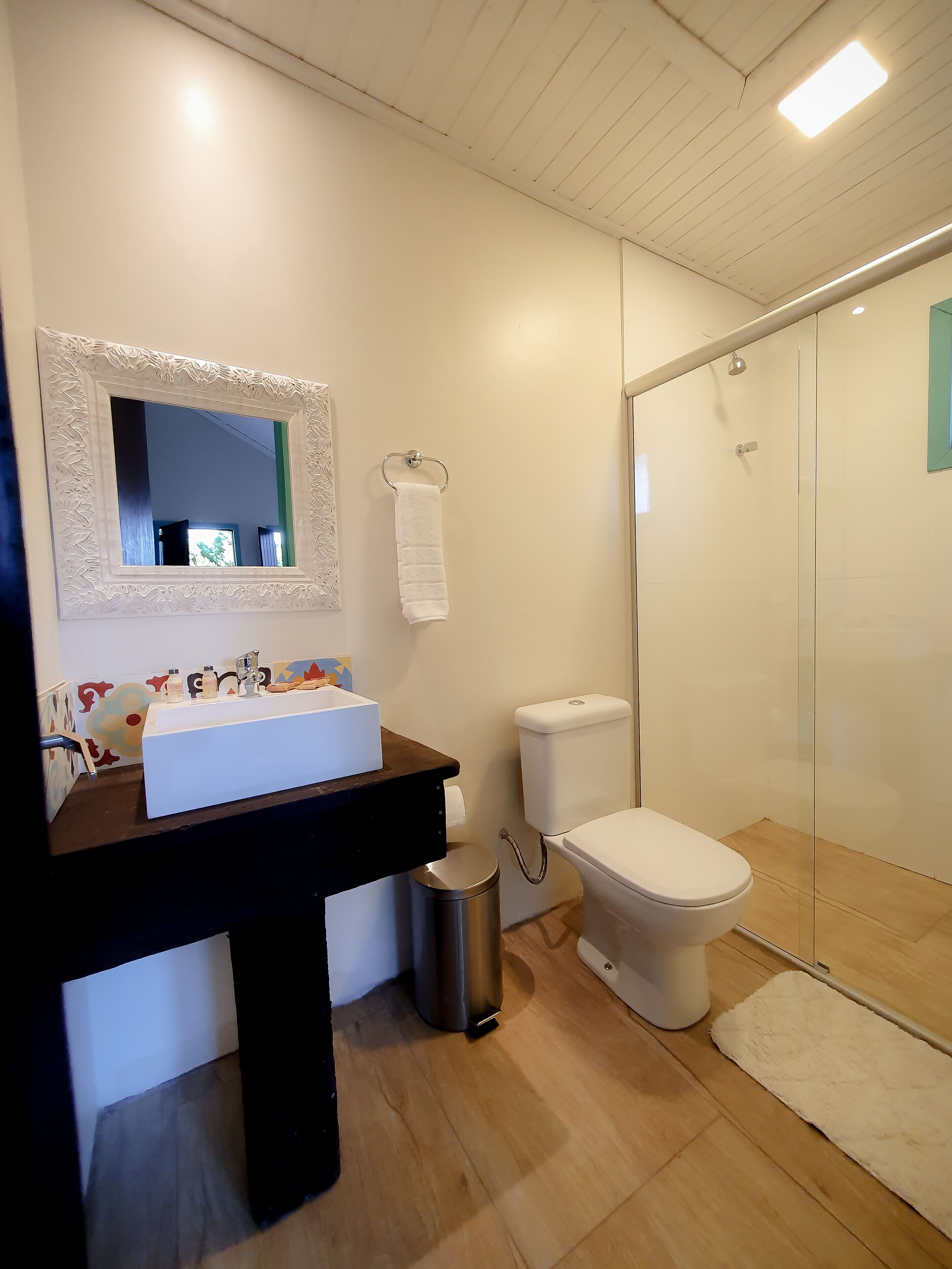 A modern bathroom with a white sink, mirror, toilet, and shower.