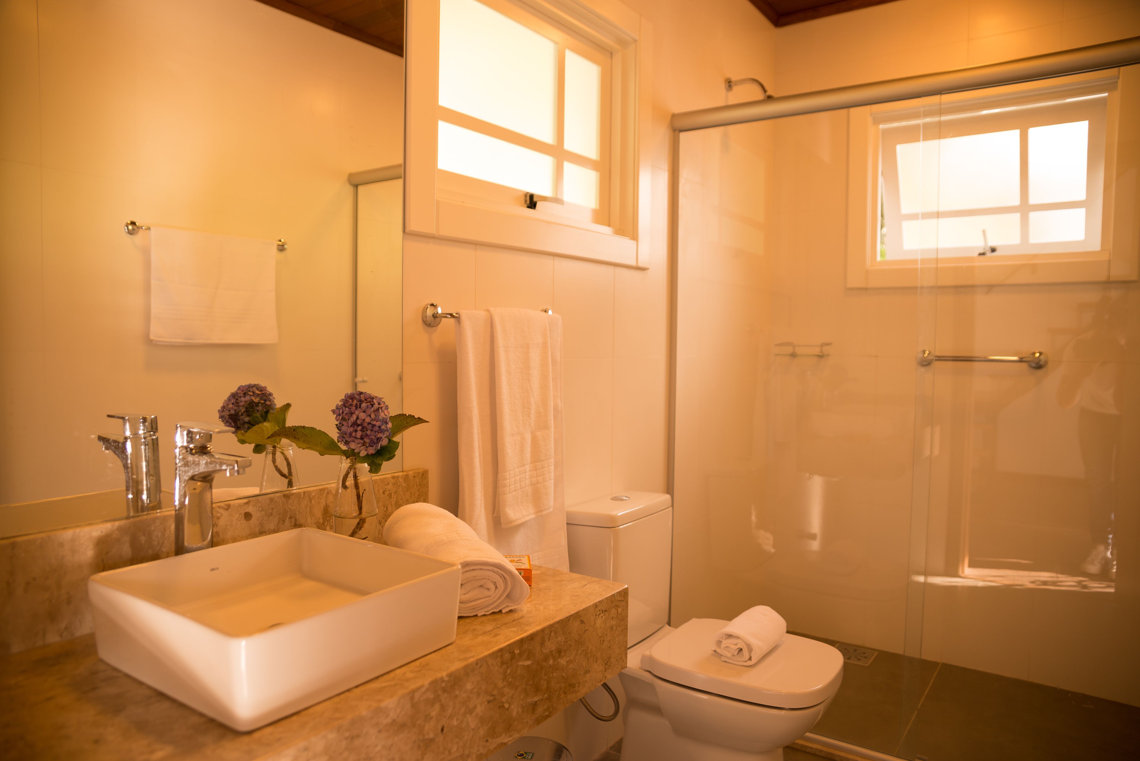 Un baño con un lavamanos grande, un inodoro y una cabina de ducha con paredes de vidrio.