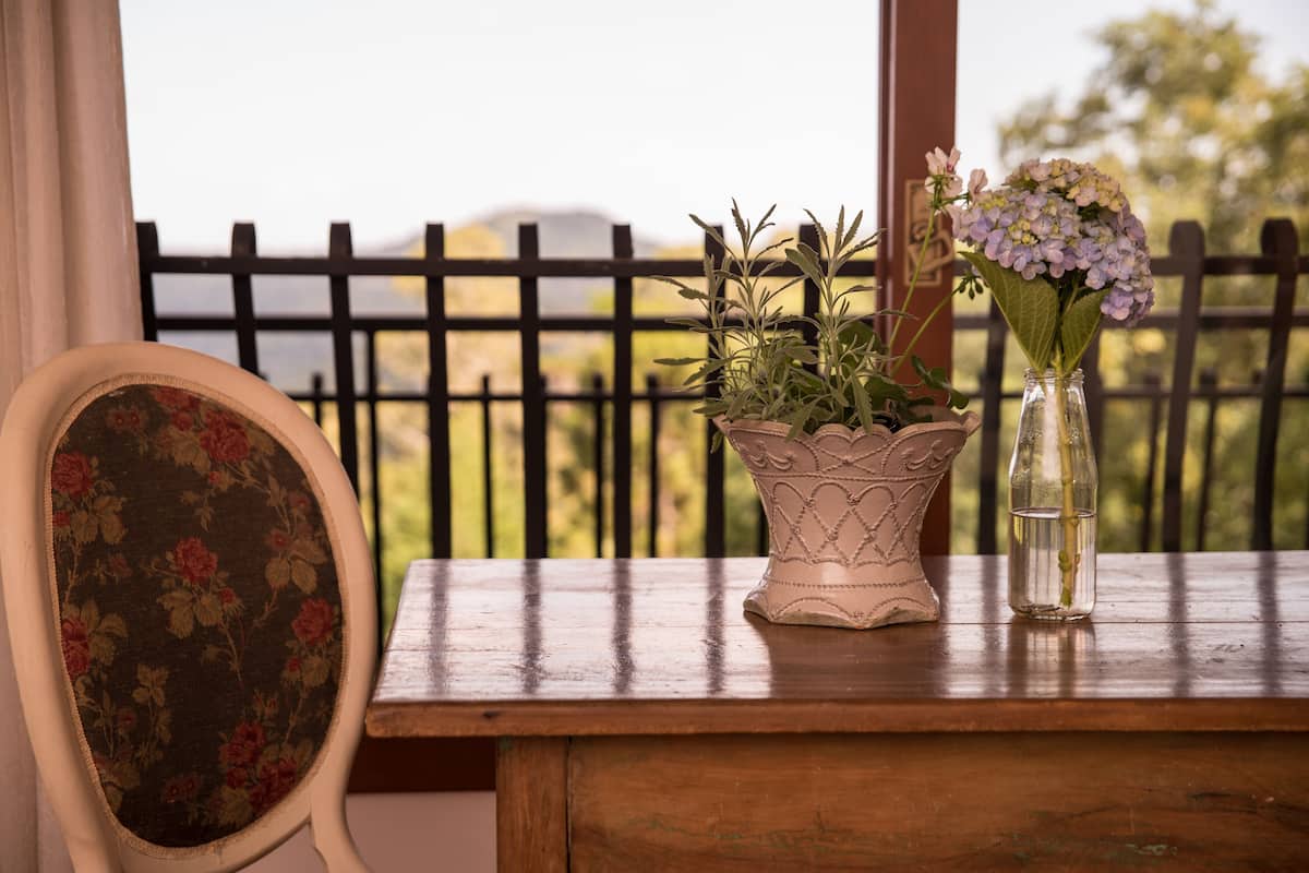 A wooden table with a vase of flowers and a potted plant.