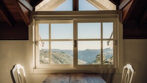 Ein Zimmer mit einem großen Fenster und Blick auf eine gebirgige Landschaft.