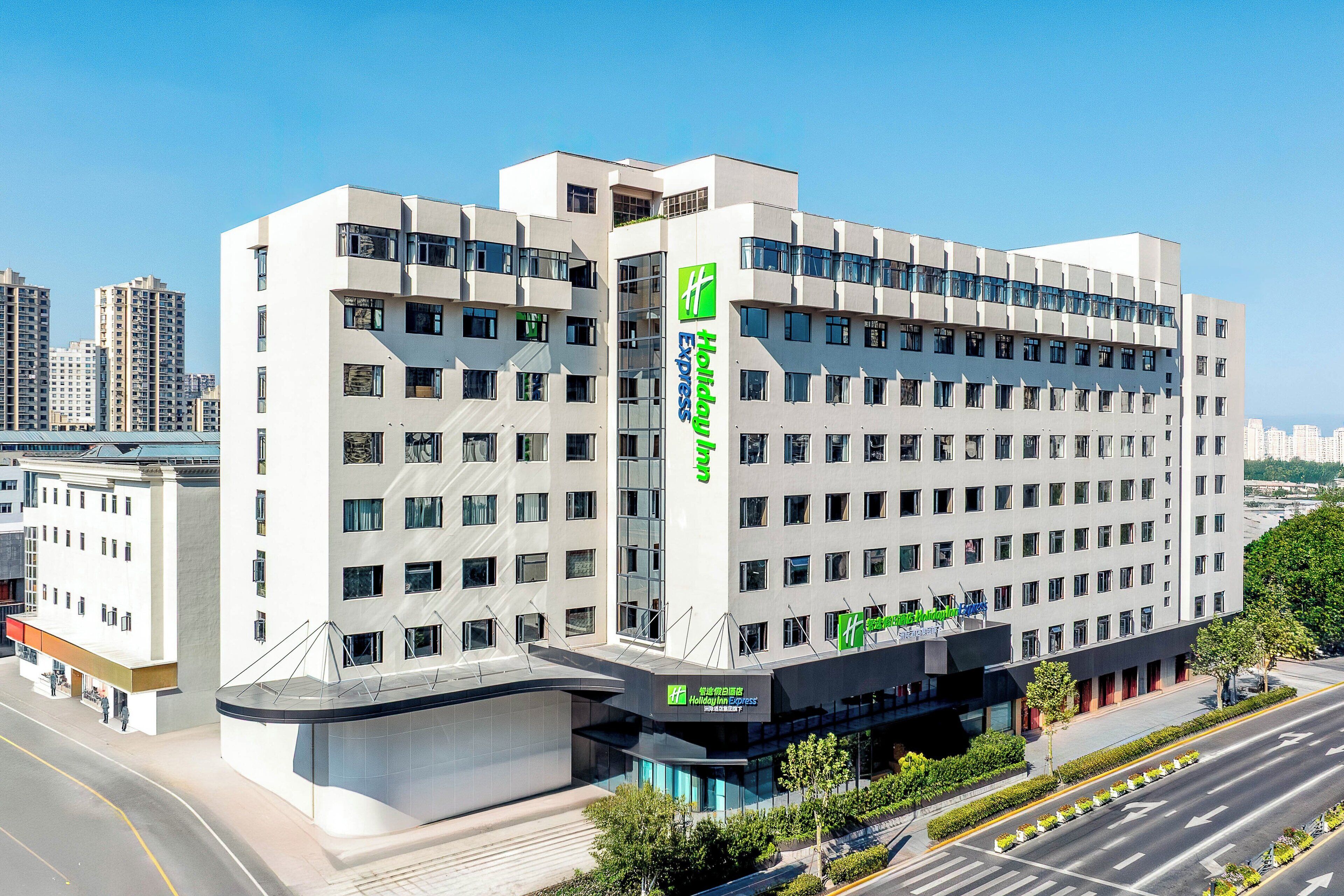Ein mehrstöckiges Hotel mit einem gut sichtbaren Holiday Inn Express Schild, das ein modernes architektonisches Design mit einer flachen Fassade und zahlreichen Fenstern aufweist.