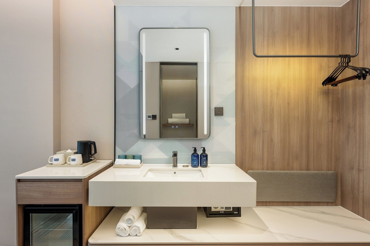 A modern bathroom with a large mirror, a sink, and a towel rack.