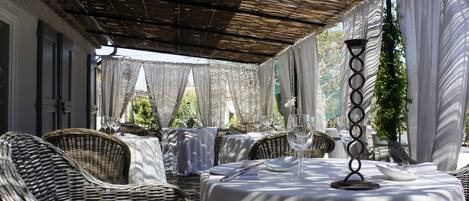 An outdoor dining area with wicker furniture and white tablecloths.