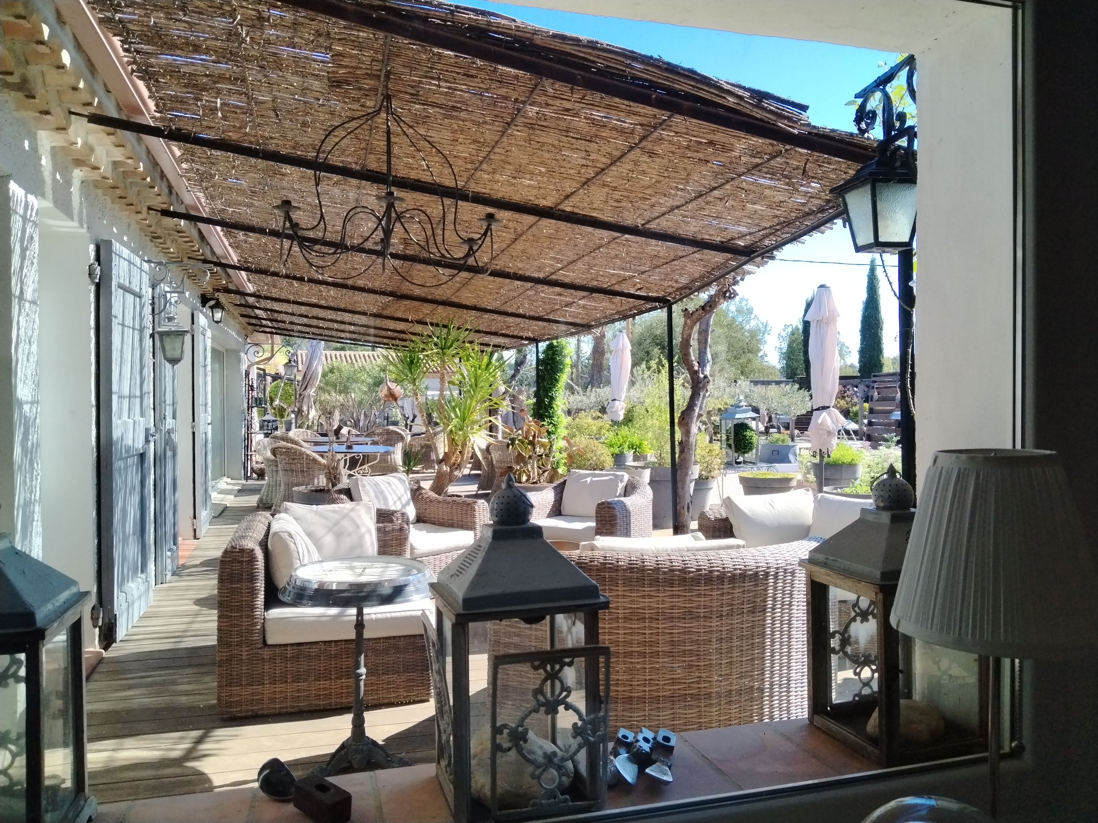An outdoor seating area with wicker furniture, a pergola, and potted plants.