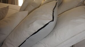 Een hotelkamer met een bed, wit beddengoed, een raam met gordijnen en uitzicht op groen.