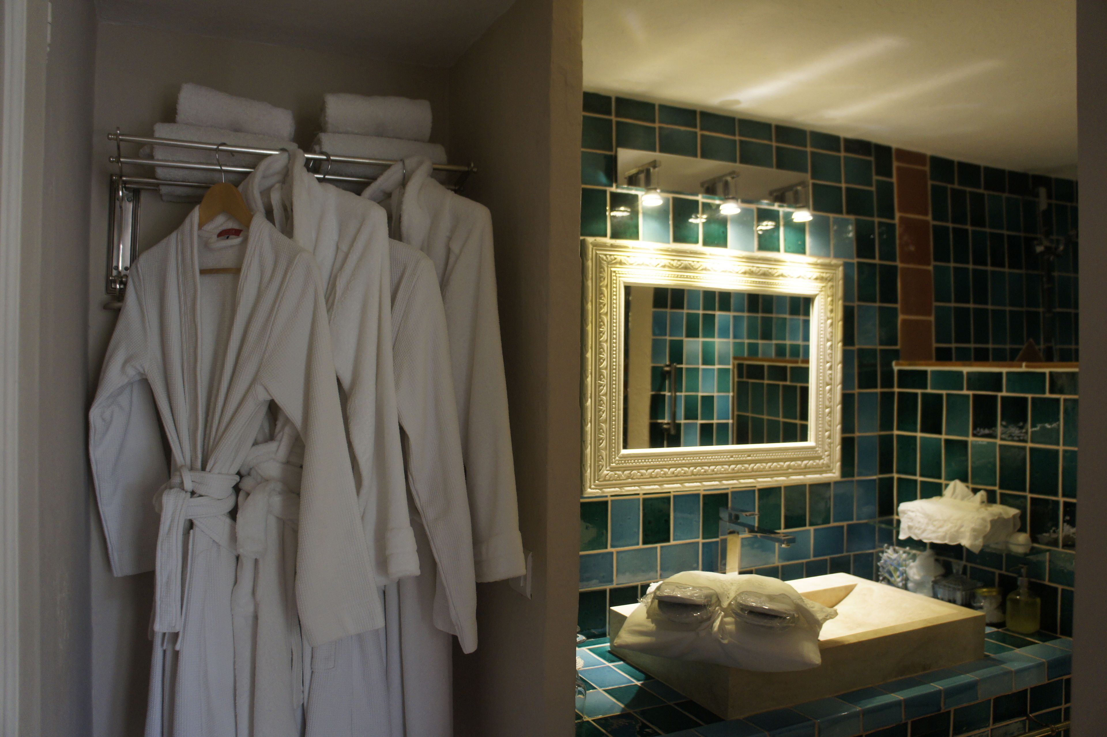 A bathroom with a blue tiled wall, a gold-framed mirror, and a sink with a towel rack above it.
