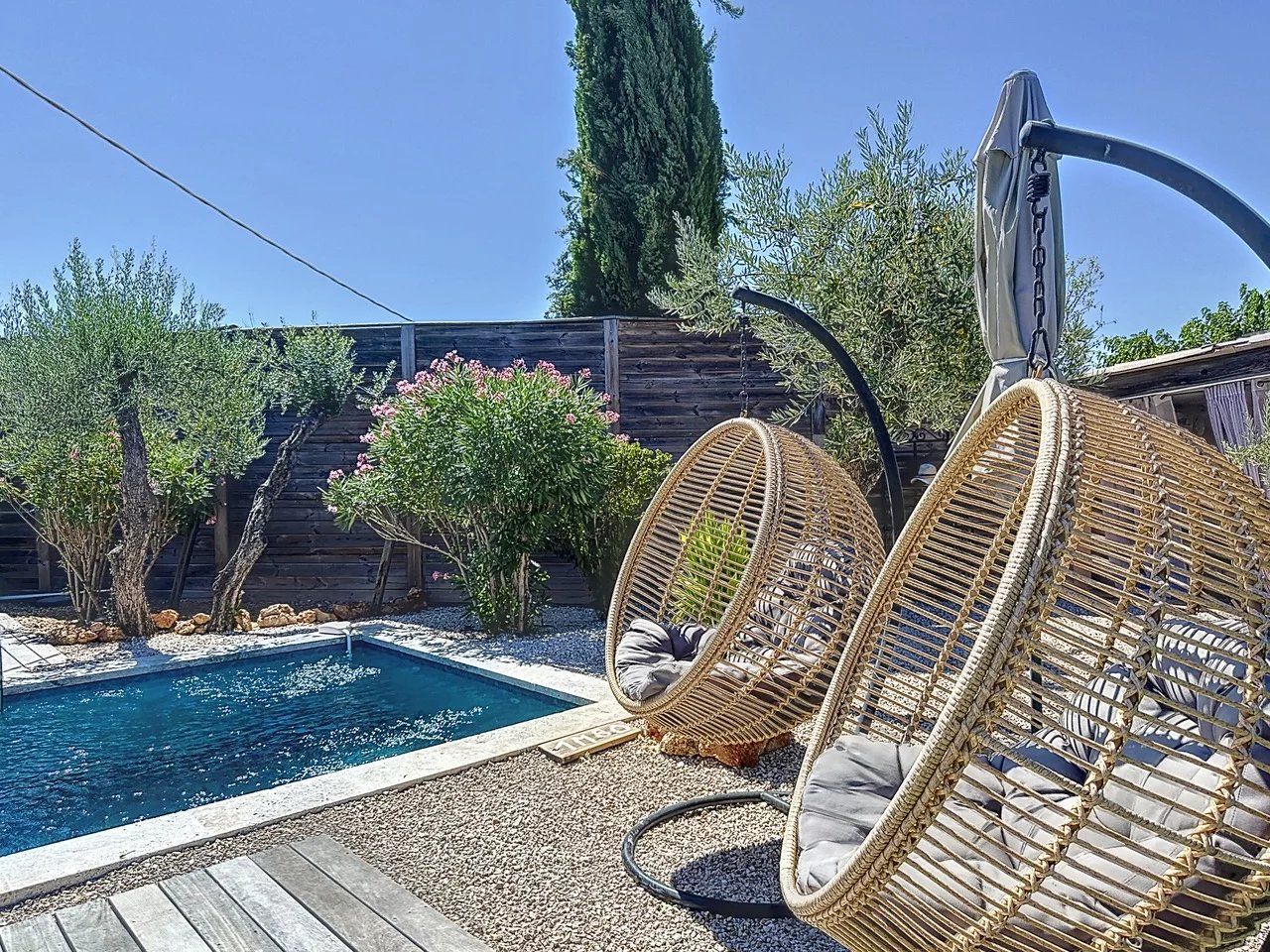 A pool area with wicker chairs and a wooden deck.