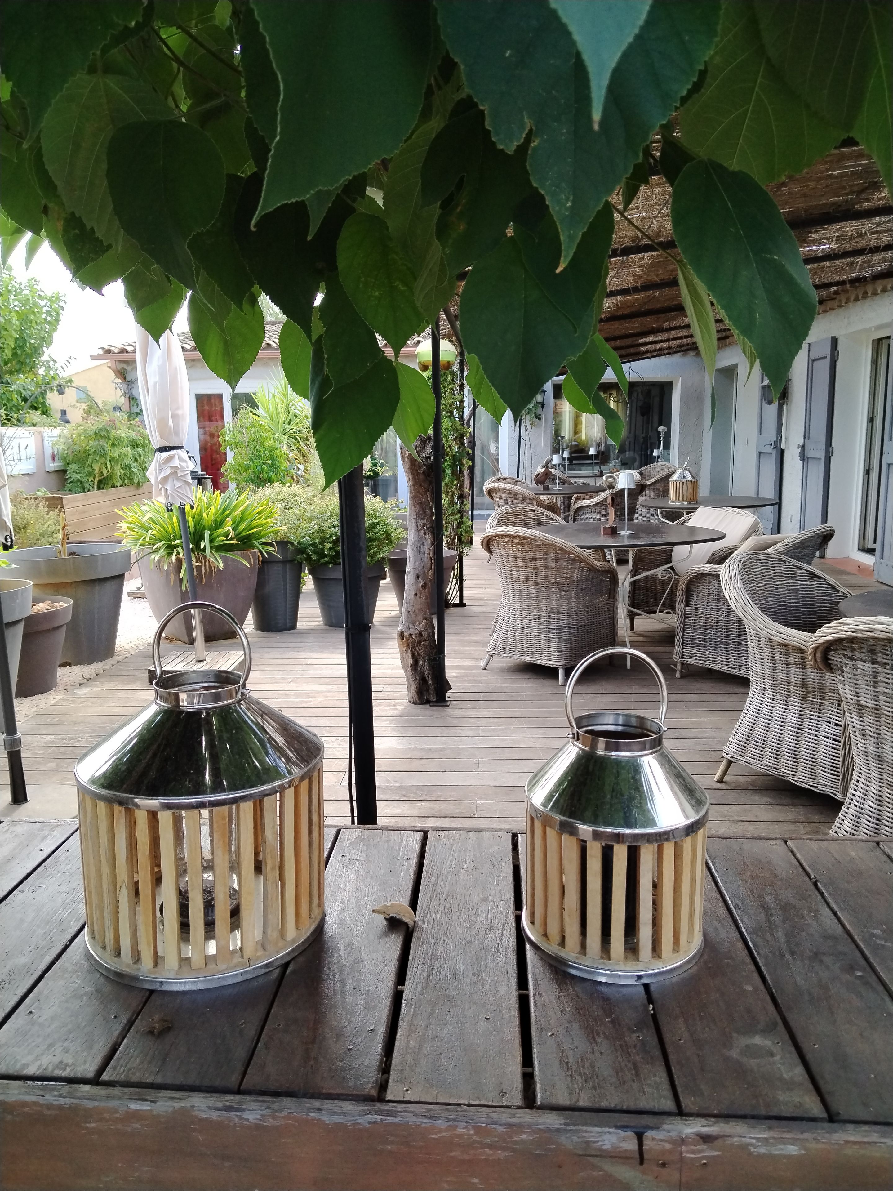 Una terraza de madera con muebles de mimbre y faroles metálicos.